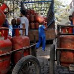 Red domestic and blue commercial LPG gas cylinders with price drop alert tag in India